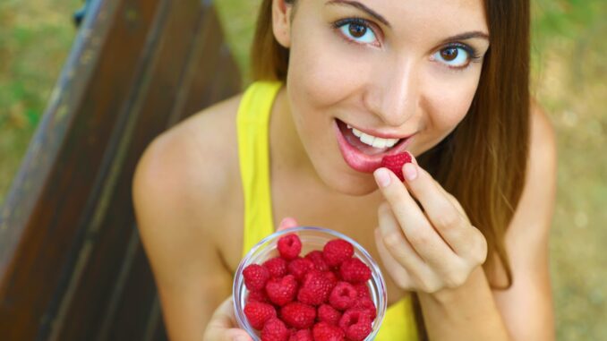 Close up of beautiful sexy woman eating berries in the park.