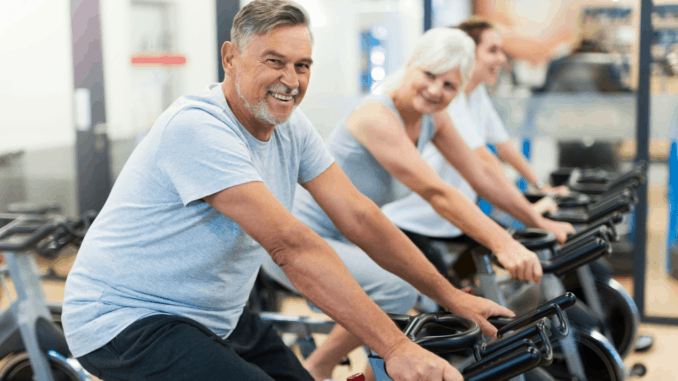 Confident seniors on exercise bikes in spinning class at gym