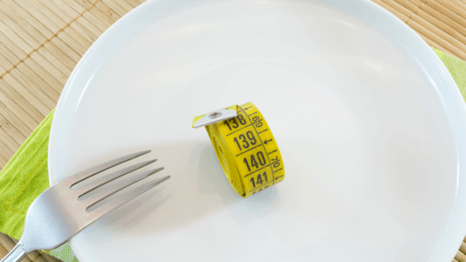Image of a plate with a measuring tape and fork. Diet concept