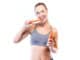 Portrait of beautiful young woman eating carrots over white background.