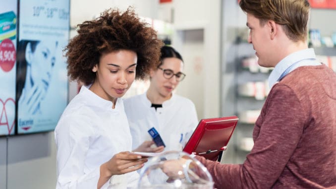 pharmacist selling prescribed medicines to a customer in a moder Dedicated female pharmacist checking a medical prescription