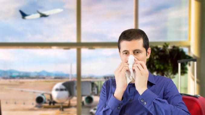 Sneezing businessman sick blowing nose at airport departure lounge
