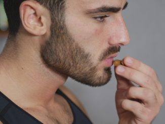 Young athletic man eating almonds in kitchen, choosing a healty lifestyle