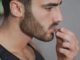 Young athletic man eating almonds in kitchen, choosing a healty lifestyle