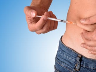 Man puncturing a dose of insulin on his belly
