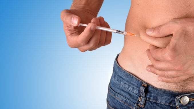 Man puncturing a dose of insulin on his belly