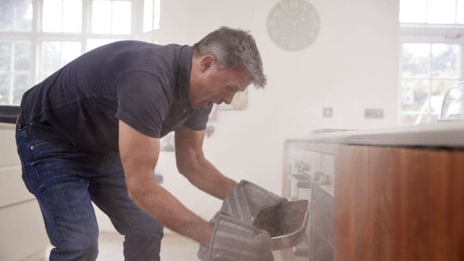 dreamstime_m_104864312 Middle aged man opening smoke filled oven in the kitchen