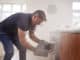 Middle aged man opening smoke filled oven in the kitchen