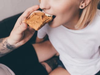 Cropped shot of men feeding girlfriend with toast with peanut butter for breakfast