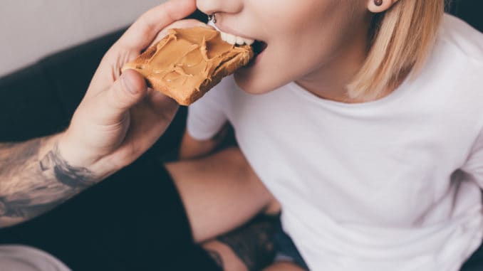 Cropped shot of men feeding girlfriend with toast with peanut butter for breakfast