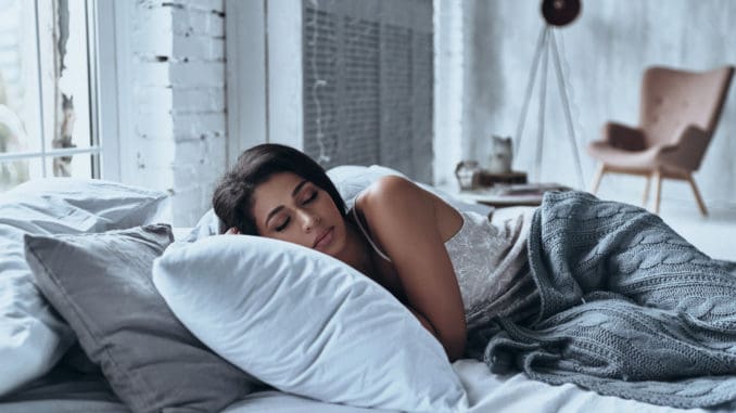dreamstime_m_106210810 Lost in a deep sleep. Attractive young woman keeping eyes closed while lying on the bed at home