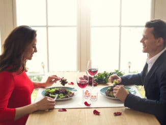 Young men and women having romantic dinner in the restaurant eating salad enjoying food