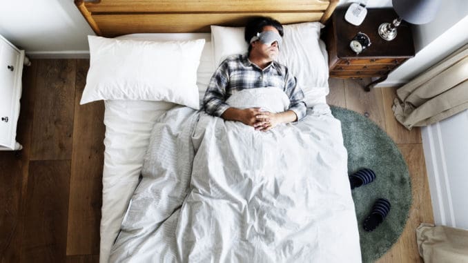 Japanese man sleeping on bed with eye mask