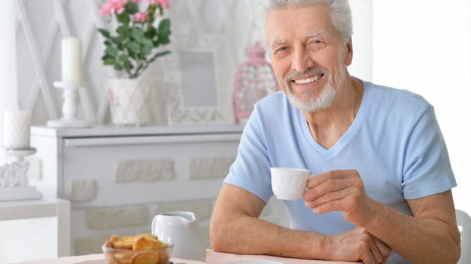 Portrait of smiling senior man drinking tea at home
