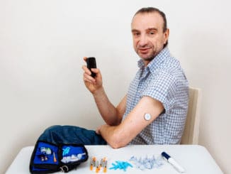 Man testing glucose level with a digital glucometer, sensor checkup glucose levels without blood. Diabetes treatment.