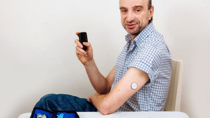 Man testing glucose level with a digital glucometer, sensor checkup glucose levels without blood. Diabetes treatment.