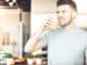 Handsome young man drinking orange juice in kitchen in the morning