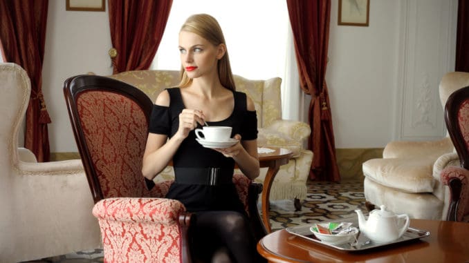 Attractive woman having tea time in a luxury hotel room