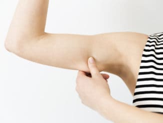 Woman checking her upper arm. Arm fat in natural light