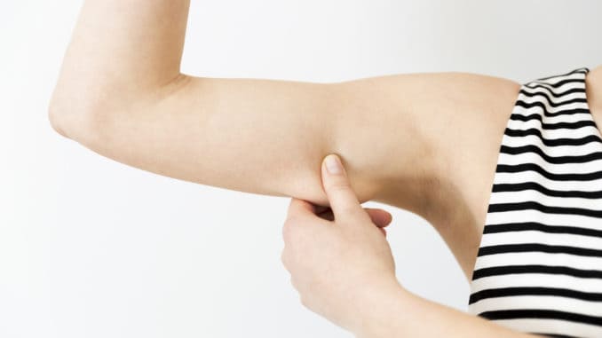 Woman checking her upper arm. Arm fat in natural light