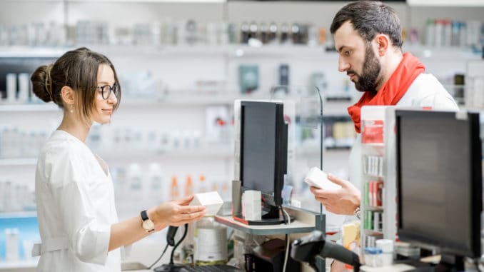 Man buying medication i the pharmacy Man buying medication standing with pharmacist at the counter of the pharmacy store