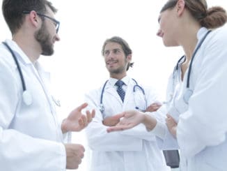 High angle view of three doctors in white coats having conversation at hospital hall