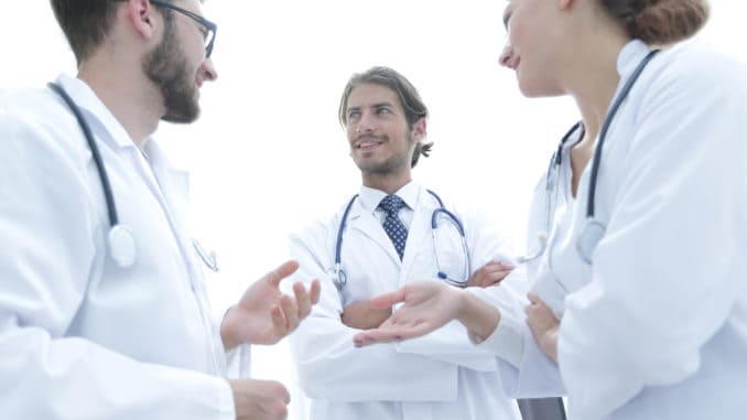 High angle view of three doctors in white coats having conversation at hospital hall