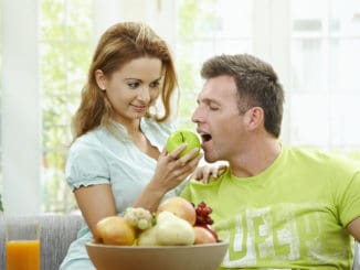 Love couple having breakfast together. Woman giving apple to her boyfriend.