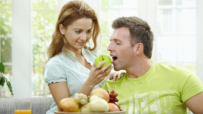 Love couple having breakfast together. Woman giving apple to her boyfriend.