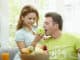 Love couple having breakfast together. Woman giving apple to her boyfriend.