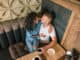 Happy young couple is drinking coffee and smiling while sitting at the cafe.