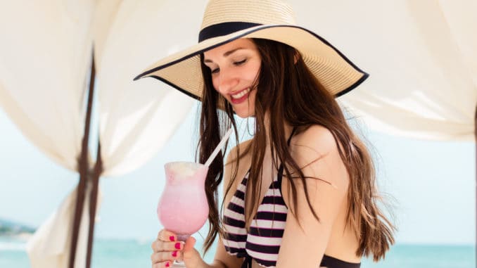 woman in beach vacation drinking a cocktail in pavilion