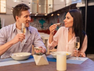 Blonde-haired man. Blonde-haired elegant men inviting her appealing women for drinking champagne and eating oysters