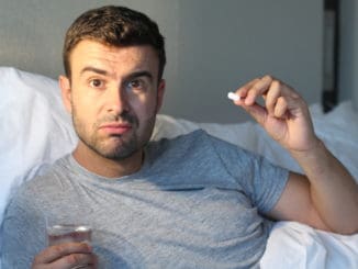 Man taking a pill in bed.