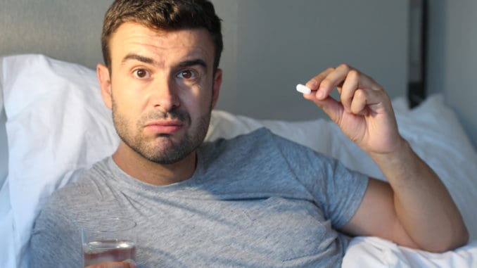 Man taking a pill in bed.