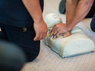 CPR training using and an AED and bag mask valve on an adult training manikin. First aid cardiopulmonary resuscitation course using automated external defibrillator device, AED.