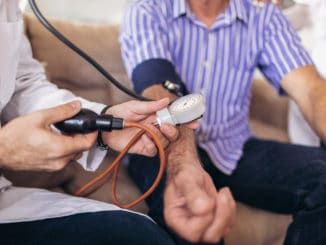 Doctor checking old man patient arterial blood pressure.