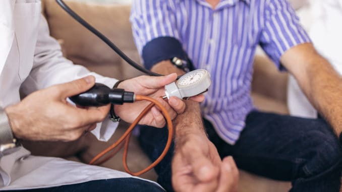 Doctor checking old man patient arterial blood pressure.