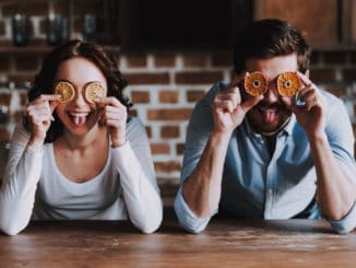 Beautiful Young Couple Having Fun in Kitchen. Handsome Smiling Woman and Man Having Fun with Colourful Oranges in Loft Kitchen. Family Preparing Dinner.