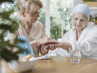 Nurse helping sick elderly women with cancer during treatment at home concept