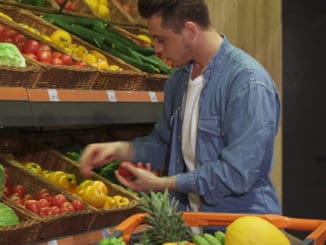 Blond caucasian guy buying fruits and vegetables at the hypermarket.