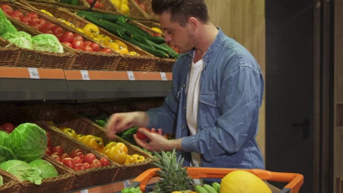 Blond caucasian guy buying fruits and vegetables at the hypermarket.