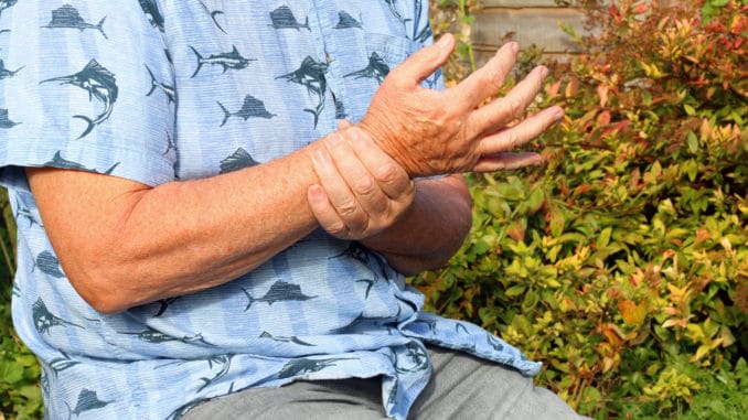 Elderly or senior man holding his wrist because of pains. Arthritis in his joints.