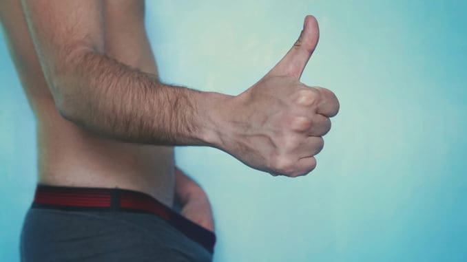 Impotence concept. Man is looking on his penis inside boxers and is showing thumb up