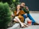 fashionable couple in velvet clothing eating fried chicken legs on street