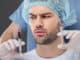handsome man in medical cap choosing beauty injections isolated on grey