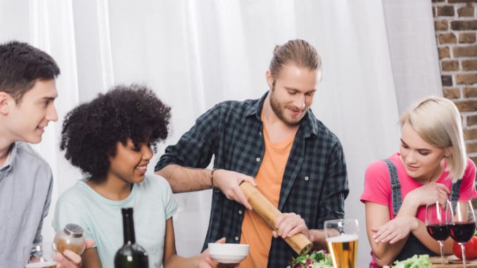 man adding spice to food with pepper grinder