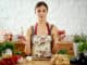 Beautiful young woman, brunette holds onions and garlic in the kitchen at a table full of organic vegetables