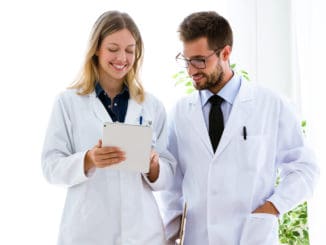 Shot of smiling young doctors looking medical reports in digital tablet in medical office