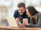 Happy couple checking laptop content on a balcony